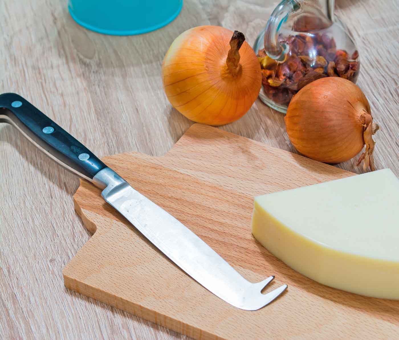 Cuchillo para quesos duros sobre tabla de corte con punta para pinchar queso